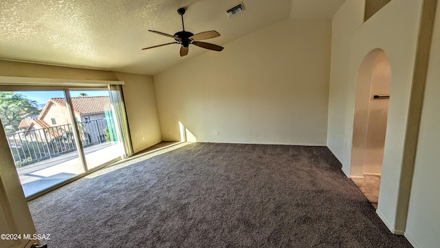 empty room with lofted ceiling, ceiling fan, carpet, and a textured ceiling