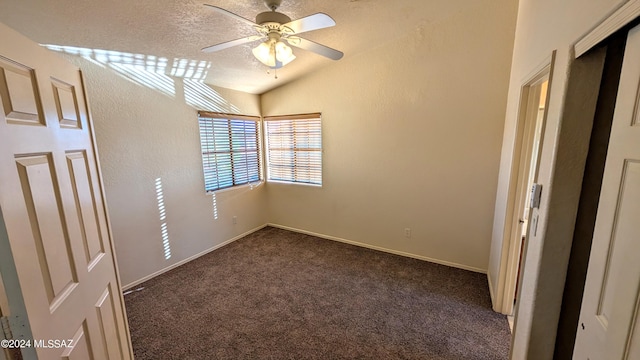 unfurnished bedroom with lofted ceiling, ceiling fan, dark carpet, and a textured ceiling