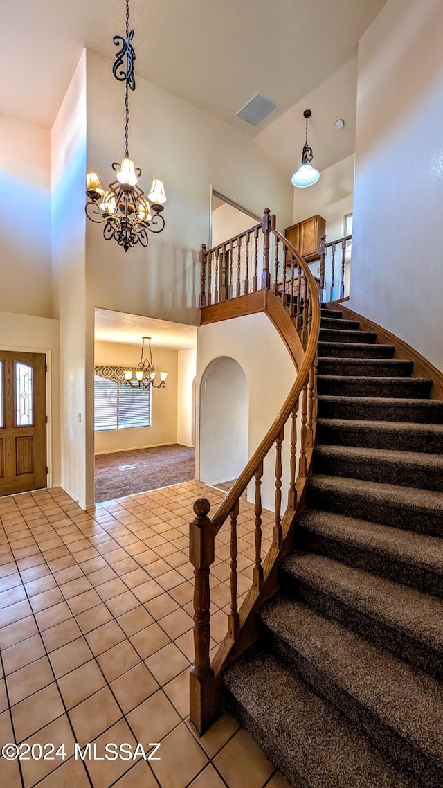 staircase featuring tile patterned flooring, a high ceiling, a chandelier, and a wealth of natural light