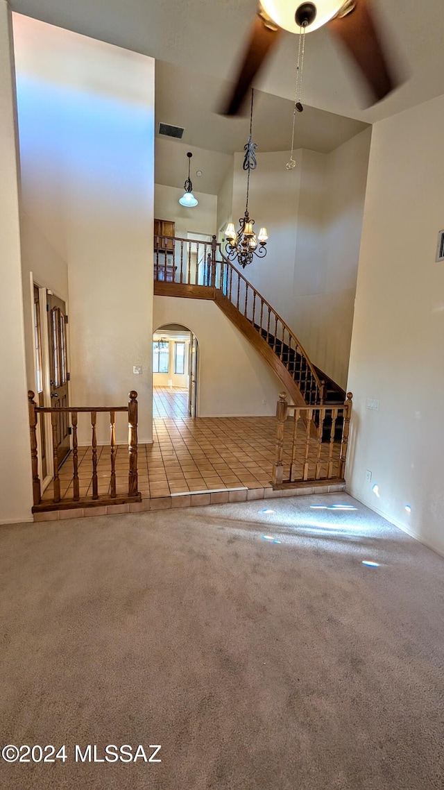 unfurnished living room featuring a high ceiling, a notable chandelier, and tile patterned flooring