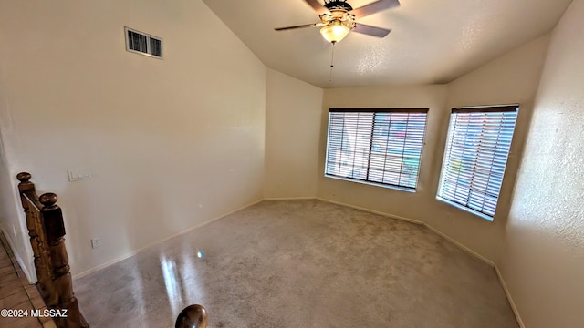 unfurnished room featuring lofted ceiling, ceiling fan, carpet floors, and a textured ceiling