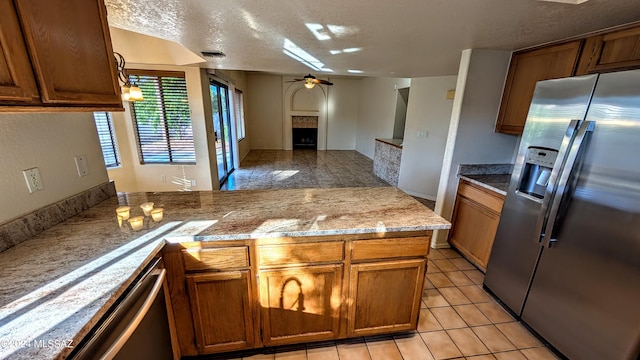 kitchen featuring a textured ceiling, ceiling fan, light tile patterned floors, and stainless steel refrigerator with ice dispenser