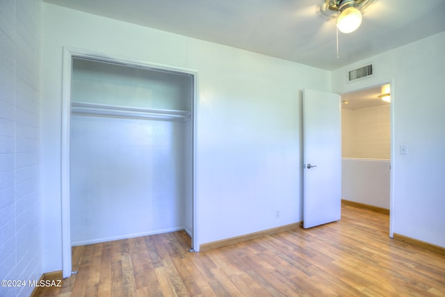 unfurnished bedroom with wood-type flooring, a closet, and ceiling fan