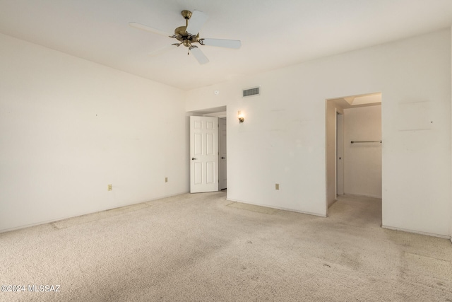 unfurnished bedroom with a walk in closet, carpet floors, a closet, and ceiling fan