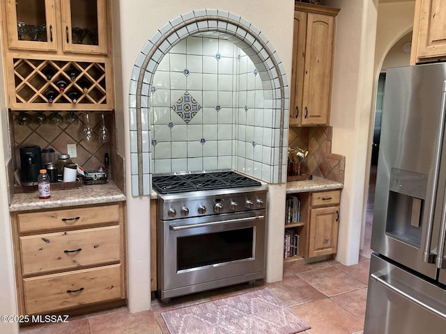 5550 W Open R Pl, Tucson, AZ 85713 - kitchen featuring appliances with stainless steel finishes, backsplash, arched walkways, light brown cabinetry, and glass insert cabinets