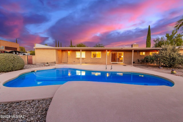 pool at dusk with a patio area