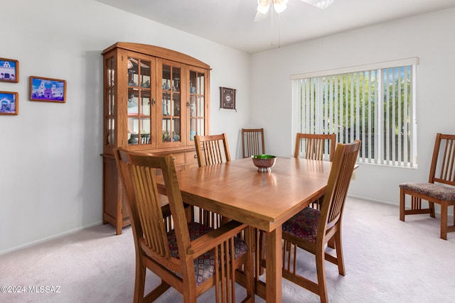 dining area with light carpet, a ceiling fan, and baseboards