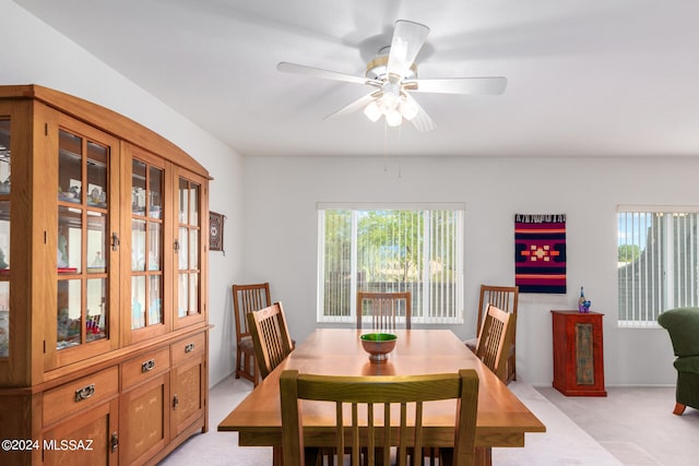 dining space with ceiling fan and light colored carpet