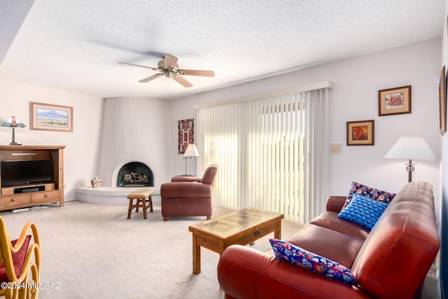 living room with a fireplace, carpet, a textured ceiling, and ceiling fan