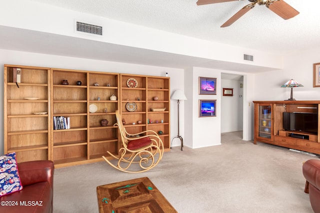 living room featuring a textured ceiling, ceiling fan, and light carpet