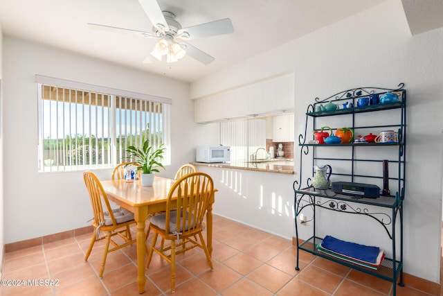 tiled dining space with ceiling fan and sink