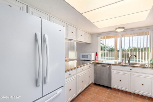 kitchen featuring white appliances, stone counters, white cabinets, sink, and light tile patterned floors