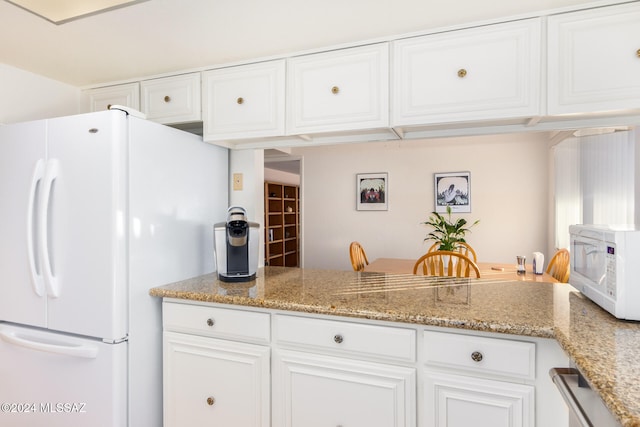 kitchen featuring a peninsula, white appliances, light stone countertops, and white cabinets