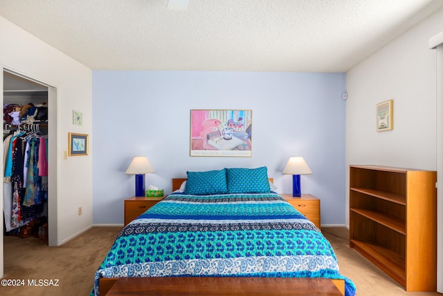 bedroom with a textured ceiling, a spacious closet, a closet, and light colored carpet