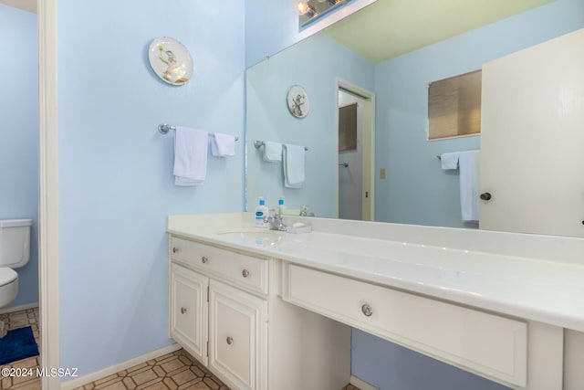 bathroom with toilet, baseboards, and vanity