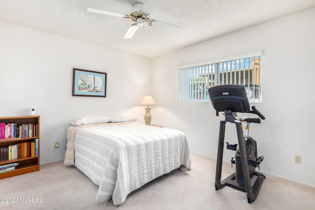 carpeted bedroom featuring ceiling fan and a textured ceiling