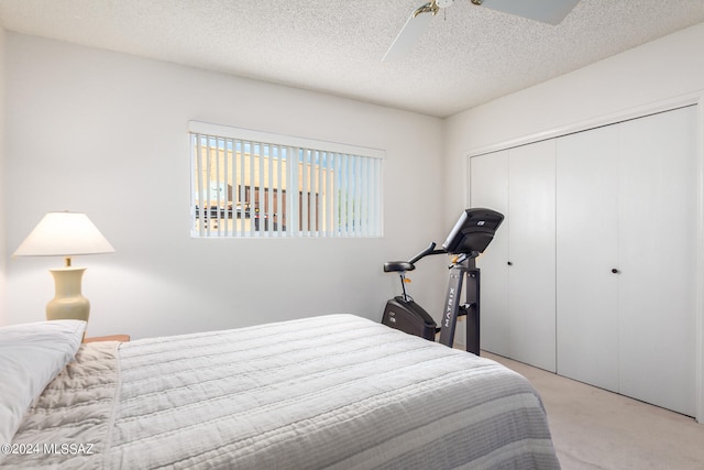 bedroom with a closet, light colored carpet, ceiling fan, and a textured ceiling