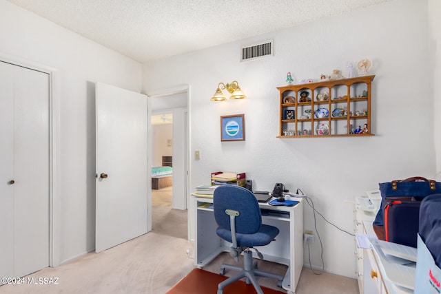 office area featuring visible vents, light carpet, and a textured ceiling