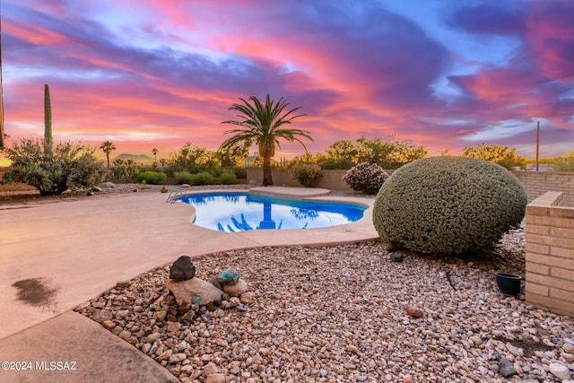 pool at dusk featuring a patio area and an outdoor pool