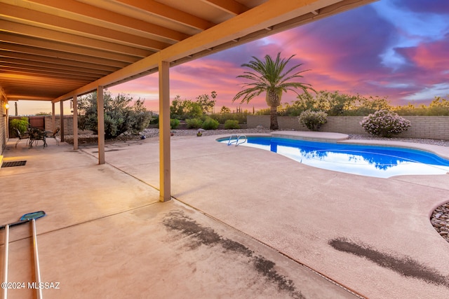 pool at dusk featuring a fenced backyard, a fenced in pool, and a patio