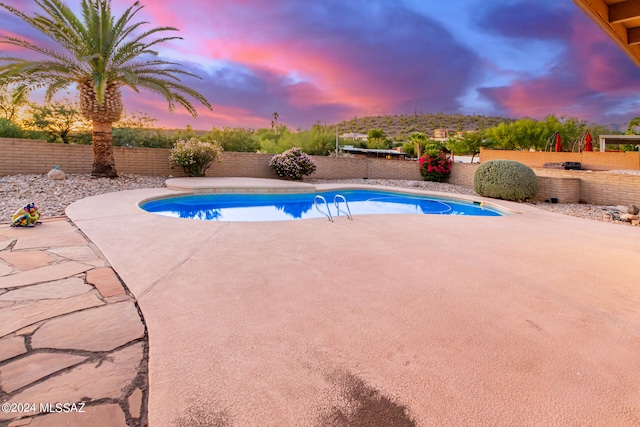 pool at dusk featuring a patio area