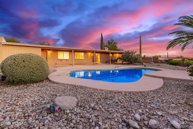 pool at dusk featuring a patio