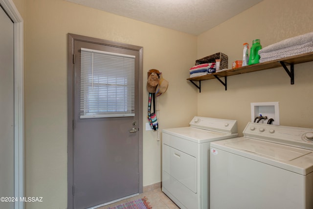 laundry area with washer and clothes dryer, light tile patterned floors, a textured ceiling, laundry area, and baseboards