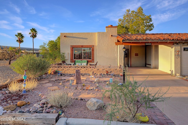 pueblo revival-style home featuring a chimney and stucco siding