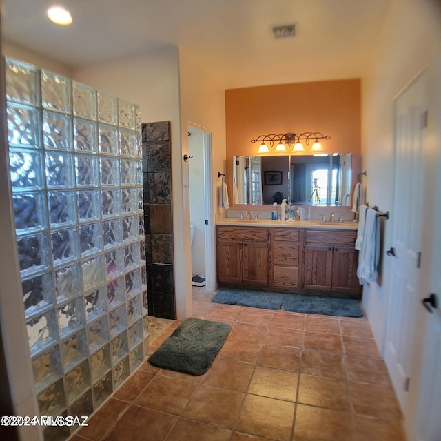 bathroom featuring tile patterned floors, a tile shower, and vanity