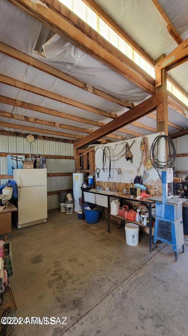 garage featuring white refrigerator, water heater, and a workshop area