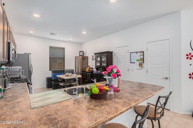 kitchen with kitchen peninsula, sink, a kitchen bar, and light tile patterned floors