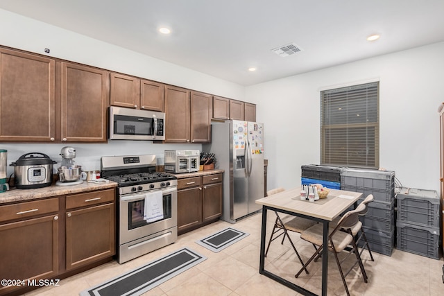 kitchen with appliances with stainless steel finishes, light tile patterned flooring, and dark brown cabinets