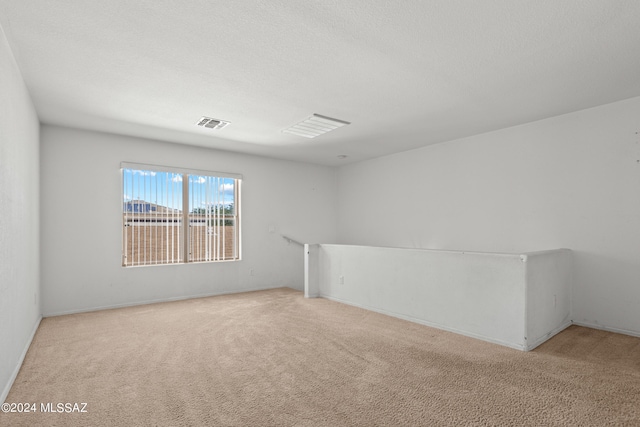 spare room featuring light carpet and a textured ceiling