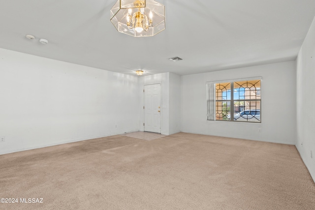 unfurnished room with a notable chandelier and light colored carpet