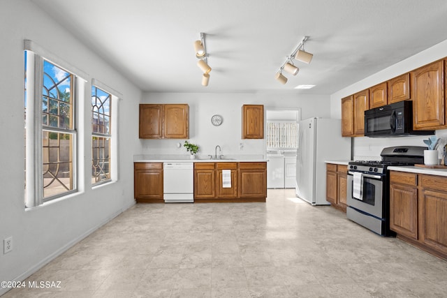 kitchen featuring white appliances, independent washer and dryer, sink, and rail lighting