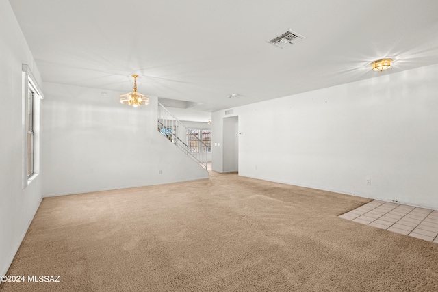 empty room featuring a chandelier and carpet flooring