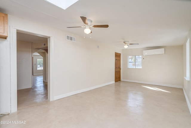 empty room featuring a skylight, ceiling fan, and a wall mounted air conditioner