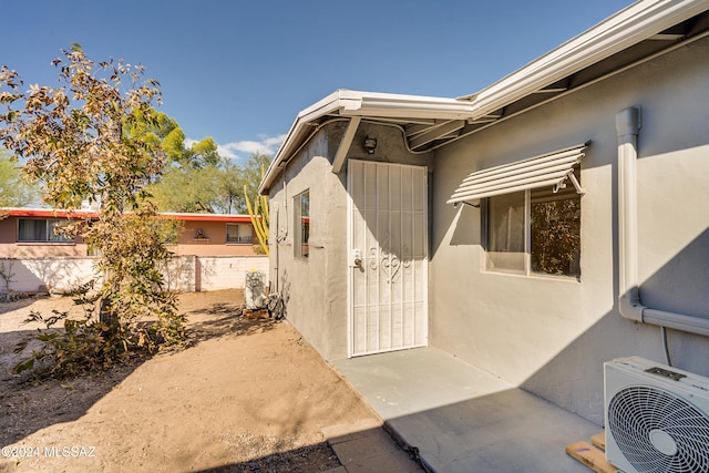 view of exterior entry with ac unit and a patio