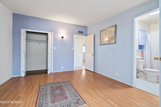 bedroom featuring a closet, ensuite bath, and wood-type flooring