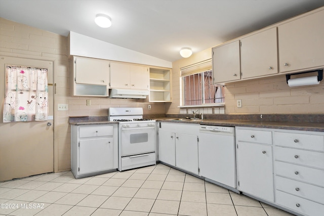 kitchen featuring sink, vaulted ceiling, light tile patterned floors, white cabinetry, and white appliances