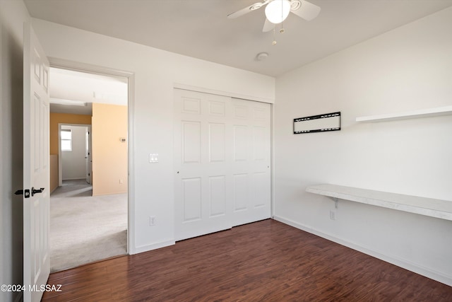 unfurnished bedroom with dark hardwood / wood-style flooring, a closet, and ceiling fan