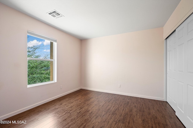 unfurnished bedroom with dark wood-type flooring and a closet