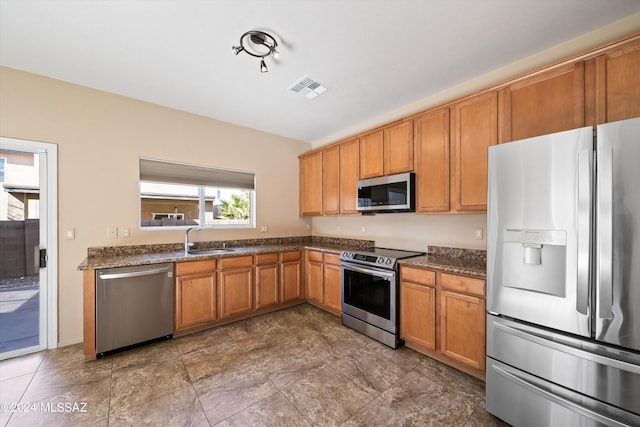 kitchen with a wealth of natural light, sink, stainless steel appliances, and dark stone countertops