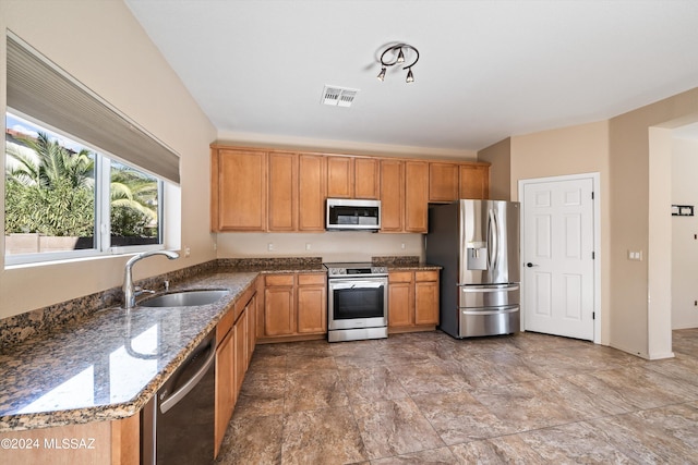 kitchen featuring sink, appliances with stainless steel finishes, and dark stone counters