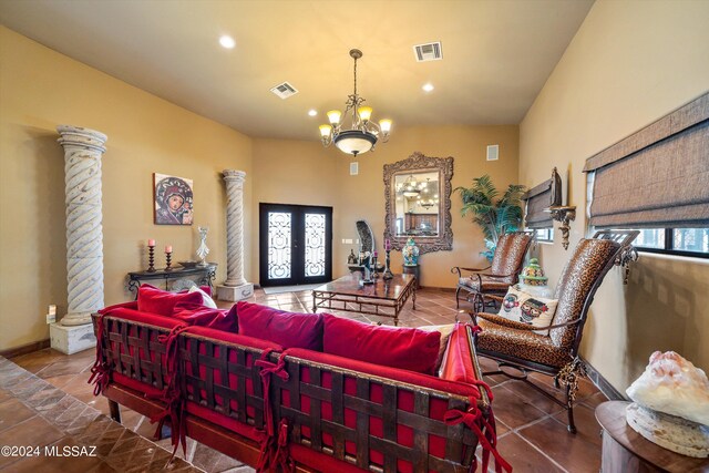 tiled living room with french doors, a notable chandelier, ornate columns, and vaulted ceiling