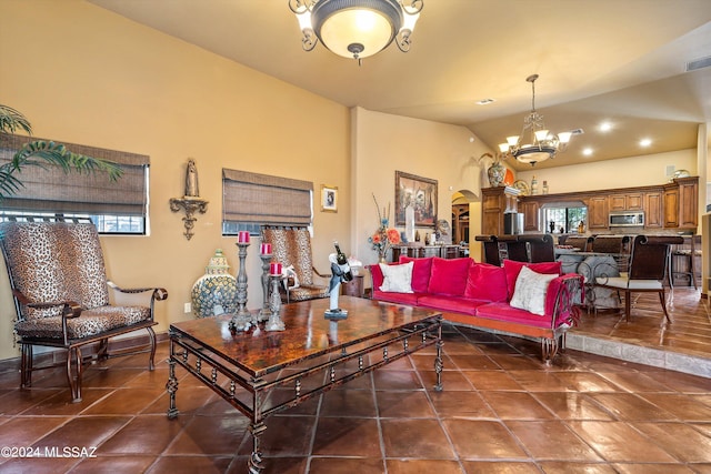 living room with lofted ceiling, a chandelier, and dark tile patterned flooring