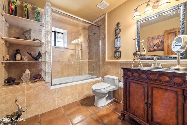 full bathroom featuring tile walls, vanity, shower / bath combination with glass door, and toilet