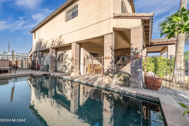 back of property with central air condition unit, a patio area, and a fenced in pool