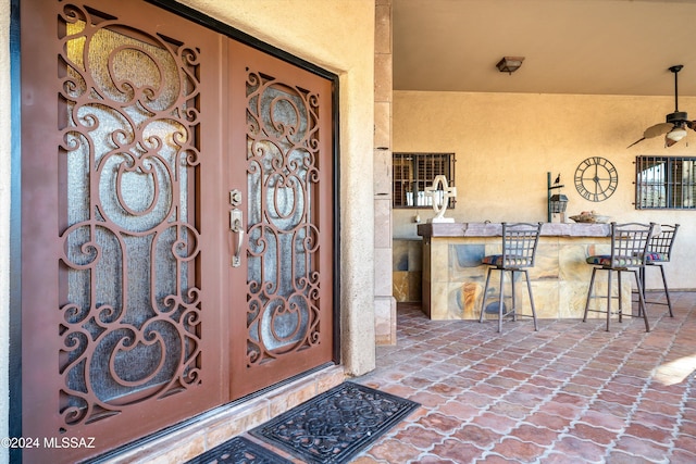 doorway to property featuring an outdoor bar, ceiling fan, and a patio