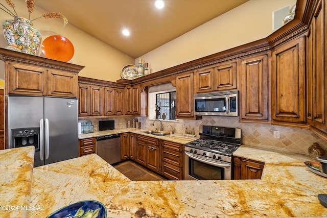 kitchen with backsplash, appliances with stainless steel finishes, light stone countertops, vaulted ceiling, and sink